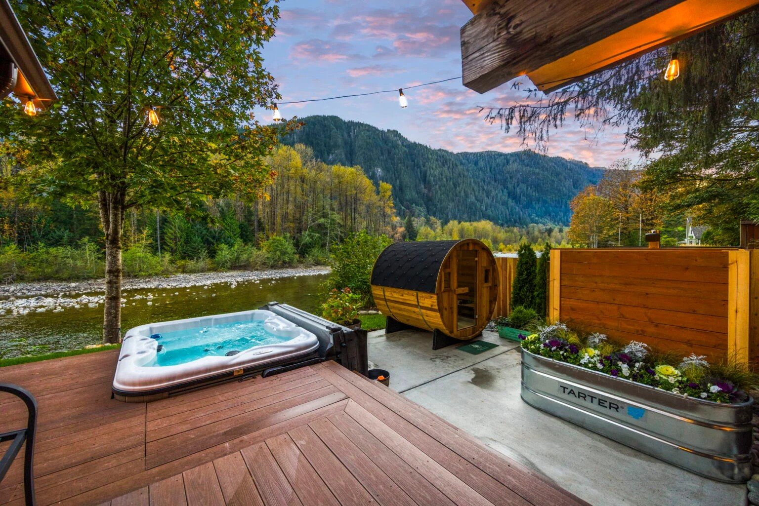 Hot tub and sauna on a riverfront deck at dusk