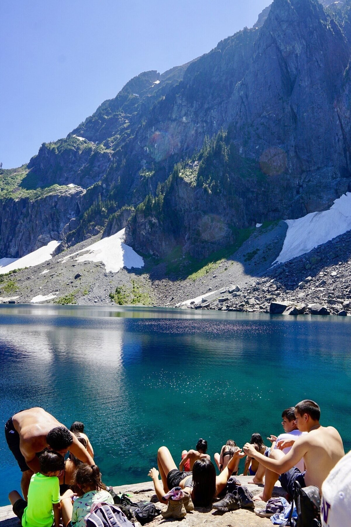 Guests gathered on the rocks at a turquoise alpine lake in the Cascades